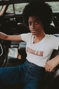 Woman sat in driving seat of a car wearing Oatmeal May the Best Man Win, Even if it's a Woman Scoop Neck Shirt by The Bee and The Fox