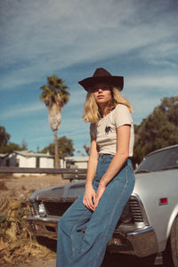 Woman leans on car in Cream Bull Shirt for Women by The Bee and The Fox
