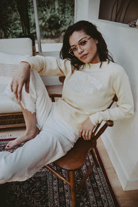Woman sat on a wooden chair wearing Love Your Mother Crop Sweatshirt for Women by The Bee and The Fox