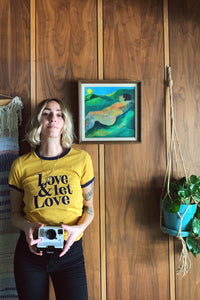 Woman holding polaroid camera wearing Love & Let Love Shirt in Mustard by The Bee and The Fox
