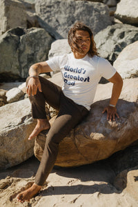 Man sat on a rock wearing World's Greatest Dad Shirt by The Bee and The Fox