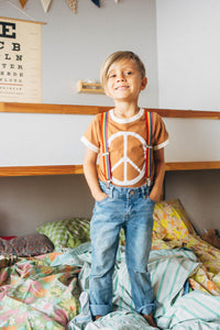 Kid stood on a bed wearing Peace Sign Ringer Tee for Kids by The Bee and The Fox