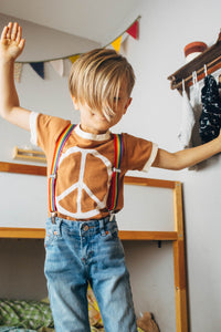 Kid stood on a bed with their arms up wearing Peace Sign Ringer Tee for Kids by The Bee and The Fox