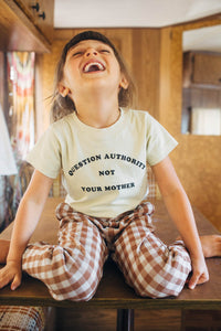 Little girl on a table laughing and wearing Question Authority Not Your Mother Shirt for Kids by The Bee and The Fox