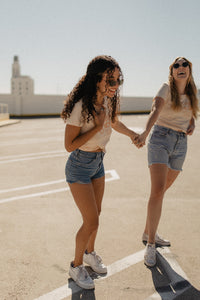 Two friends laughing, holding hands and wearing Behind Every Great Woman There's a Shit Ton of Other Dope Ass Women Shirt by The Bee and The Fox